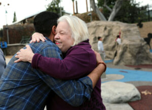 Bell councilmember Ali Saleh gets a hug from a woman at a park in Bell, California